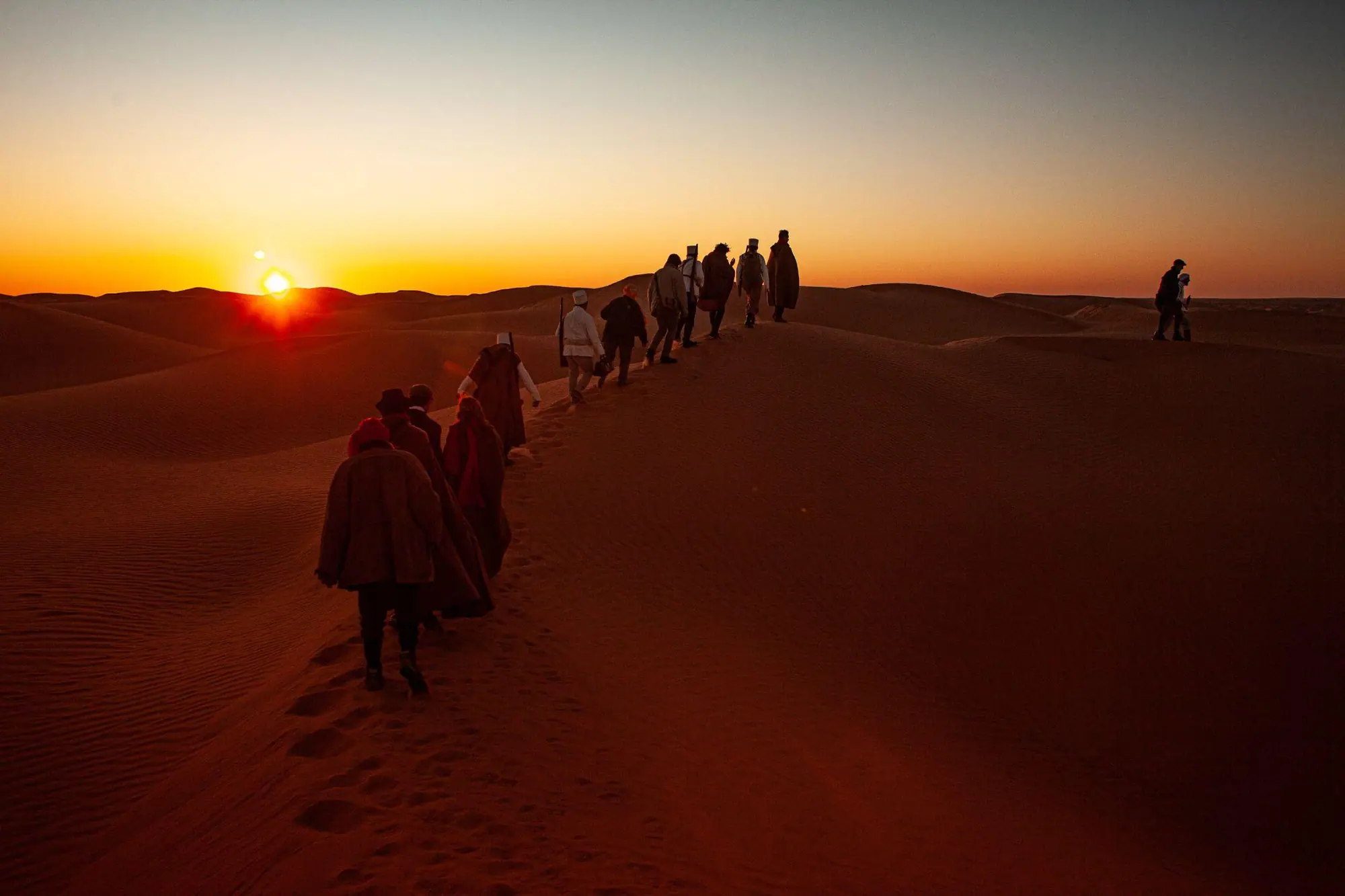 A caravan crossing the dunes at sunset during Expedition Sahara