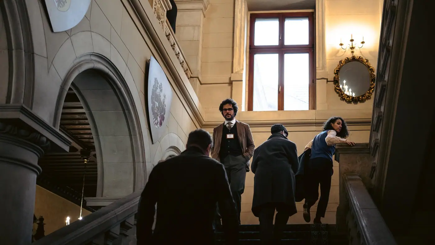 Figures silhouetted in an arched castle corridor