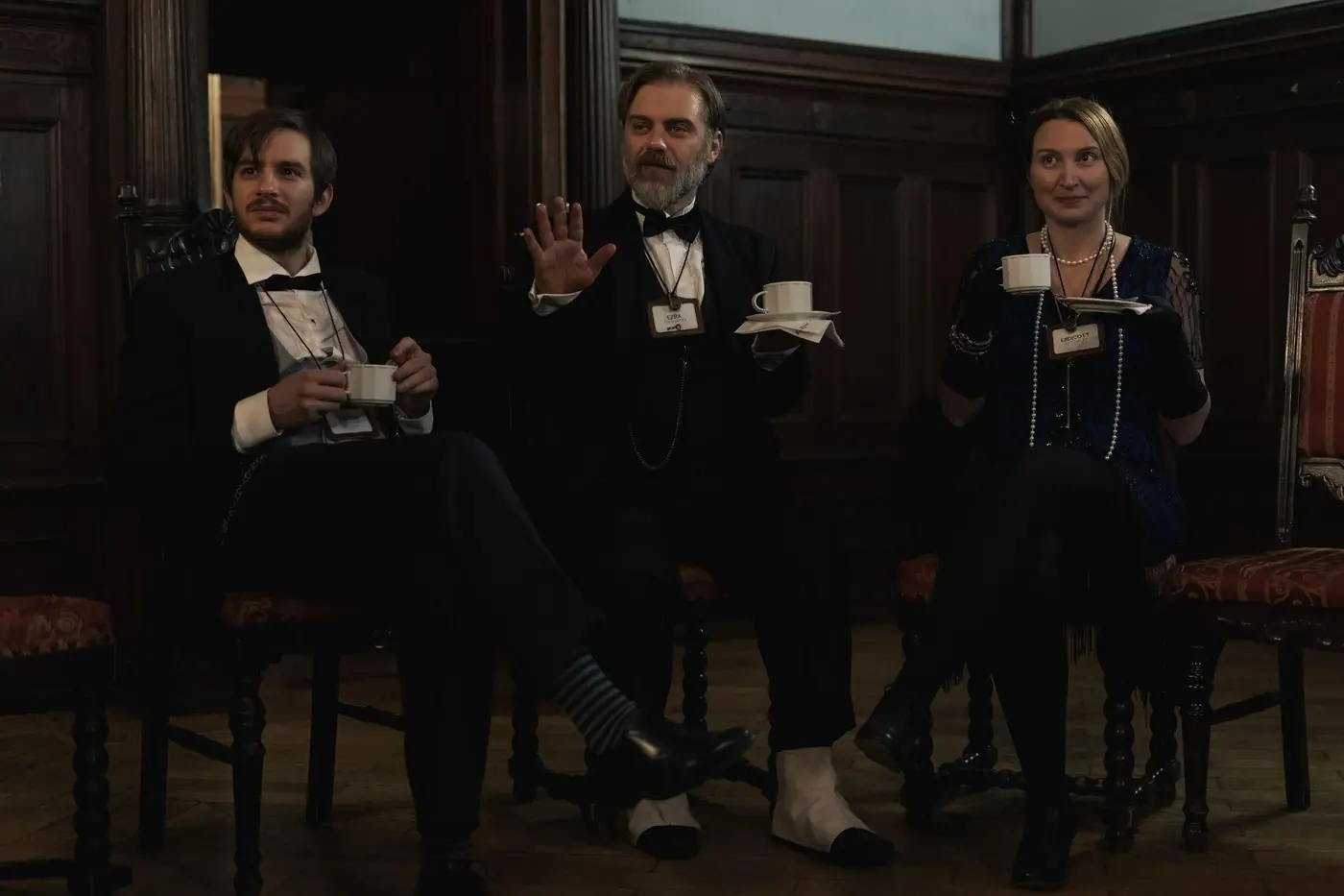 Players in evening dress in a wood-panelled room