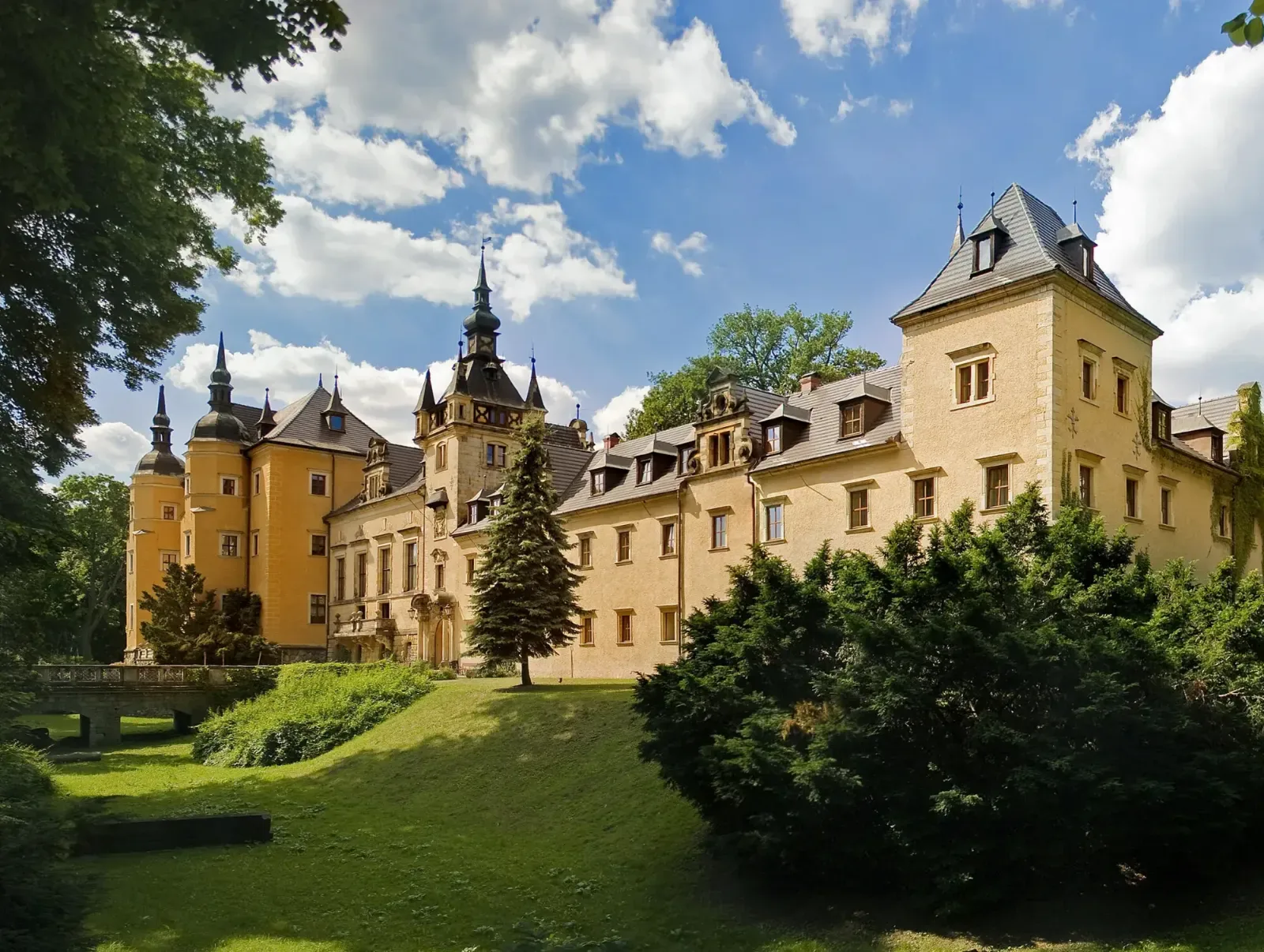 Kliczków Castle across the park lawn, its towers against a summer sky