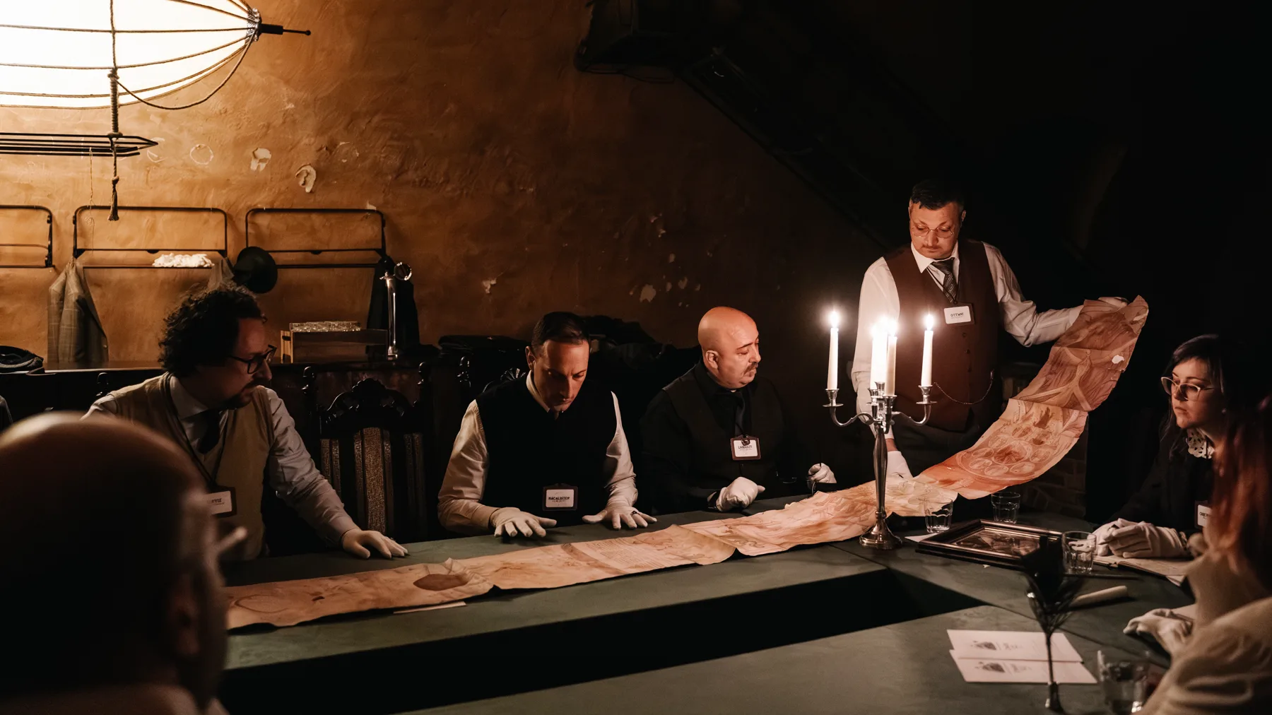 Scholars unroll an ancient scroll by candlelight
