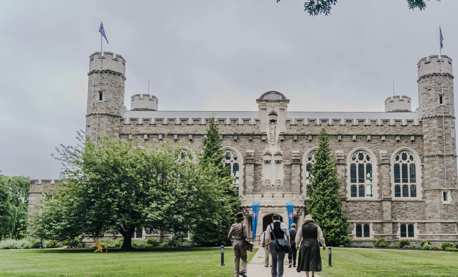 Players in period costume walk toward the towers of the campus