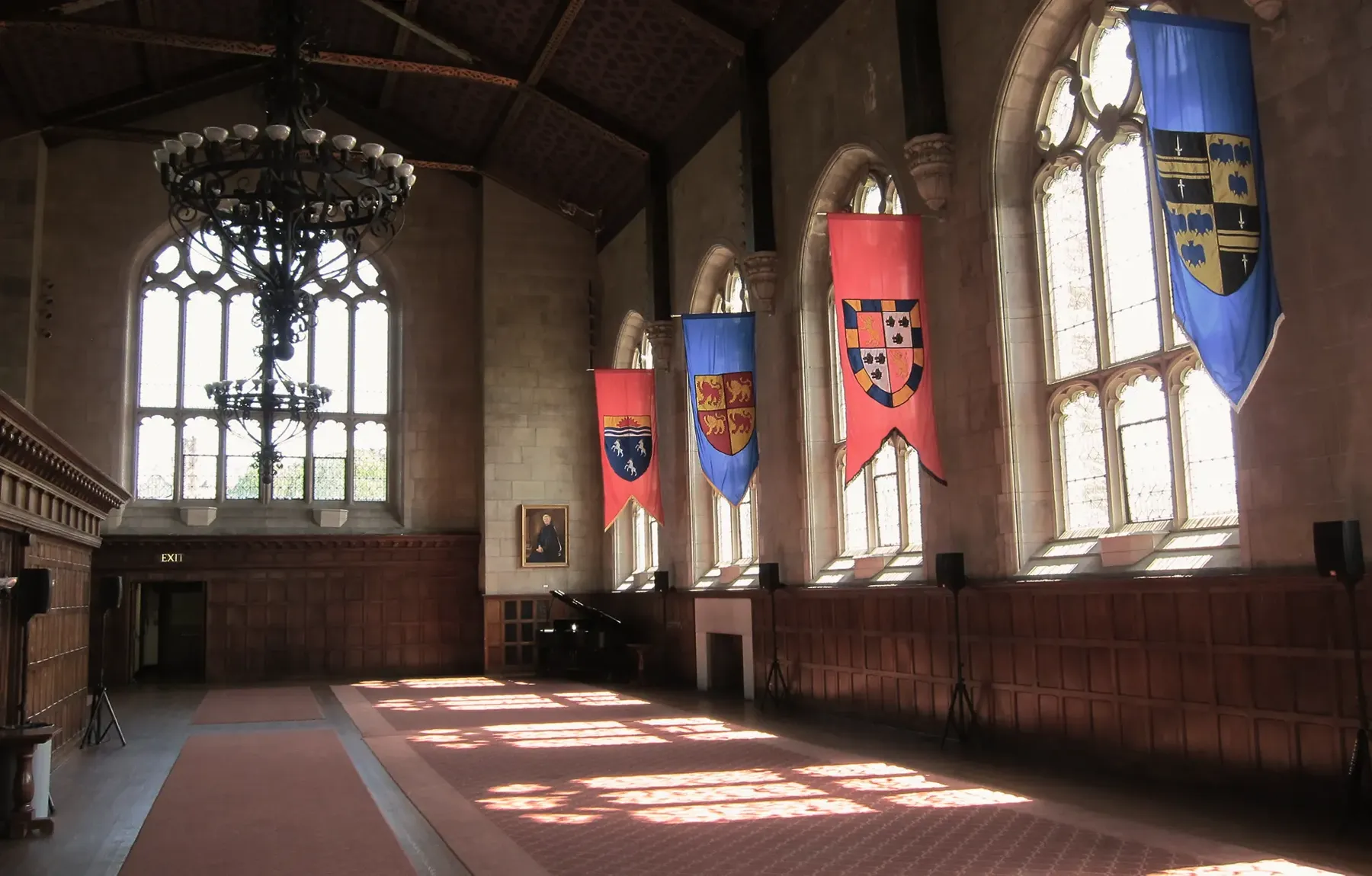 A panelled hall hung with heraldic banners, sunlight across the floor
