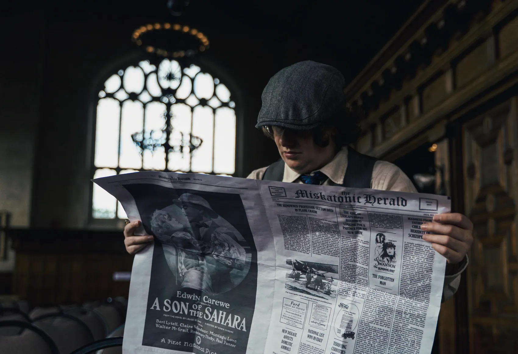 A student reads the Miskatonic Herald in the great hall