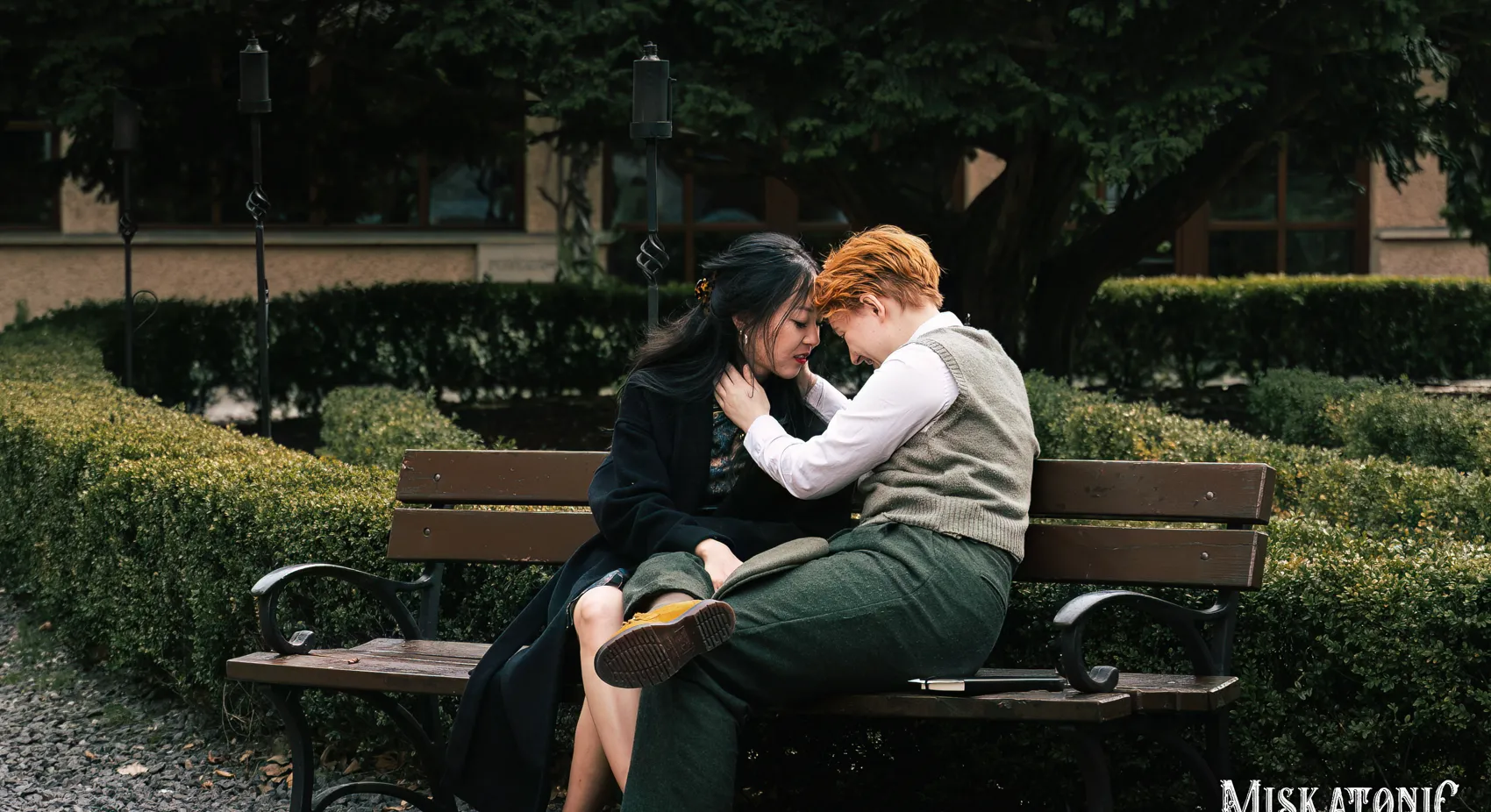Two characters in a close, tense moment on a garden bench