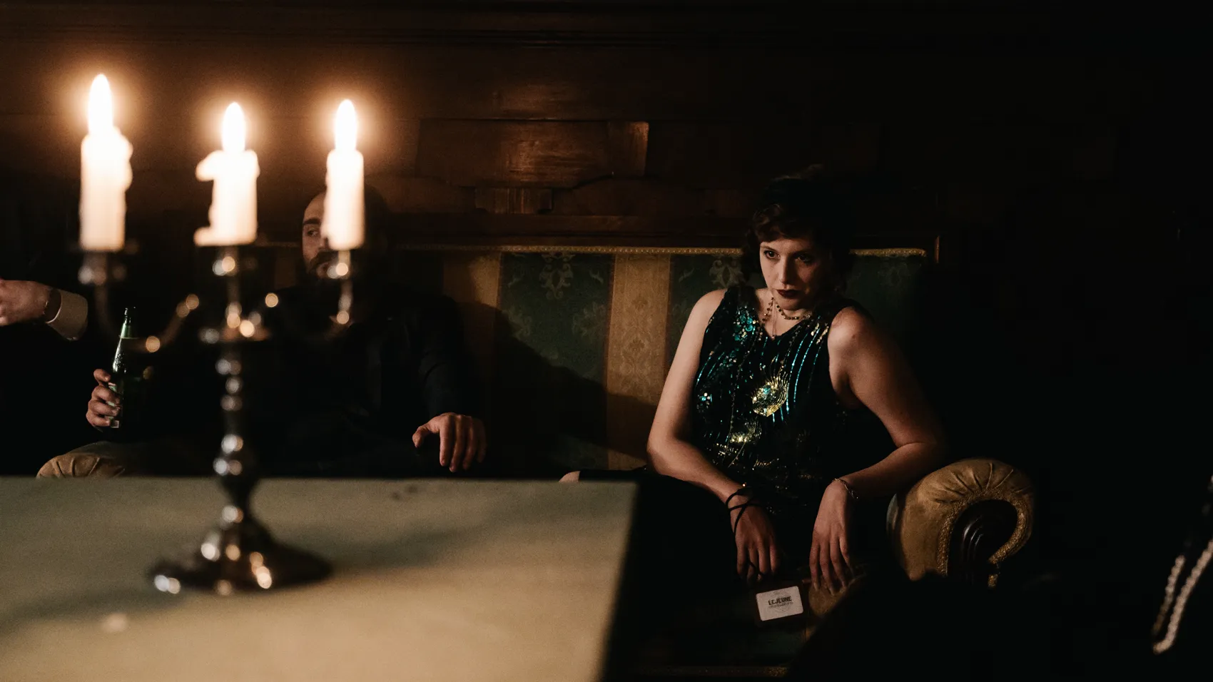 A woman in a beaded dress beside a candelabra
