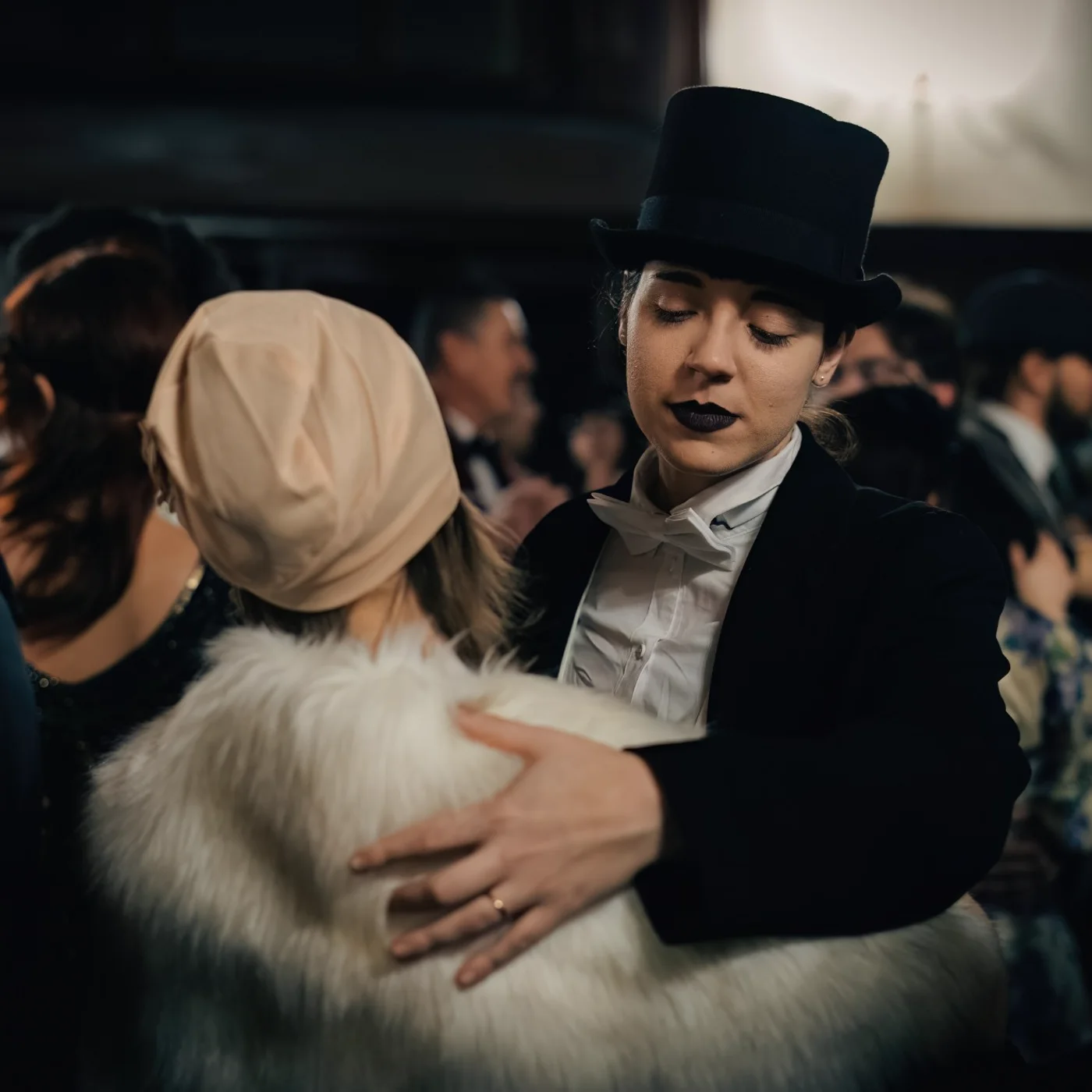 Two characters dancing close at the ball, one in a top hat