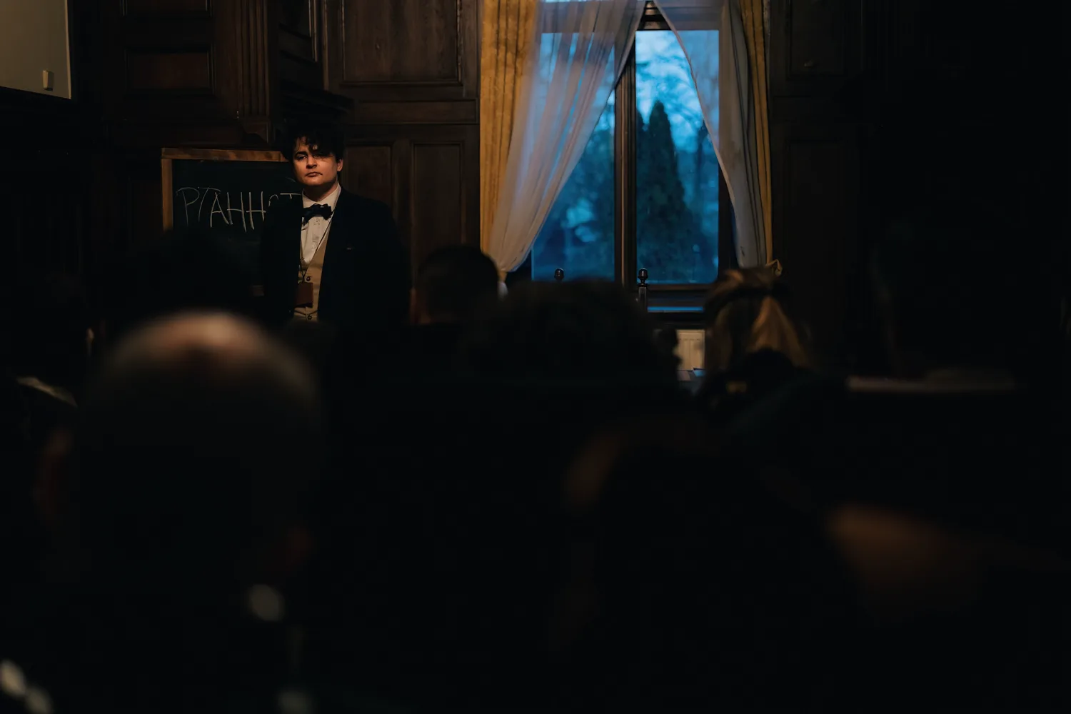 A professor speaks before a moonlit window